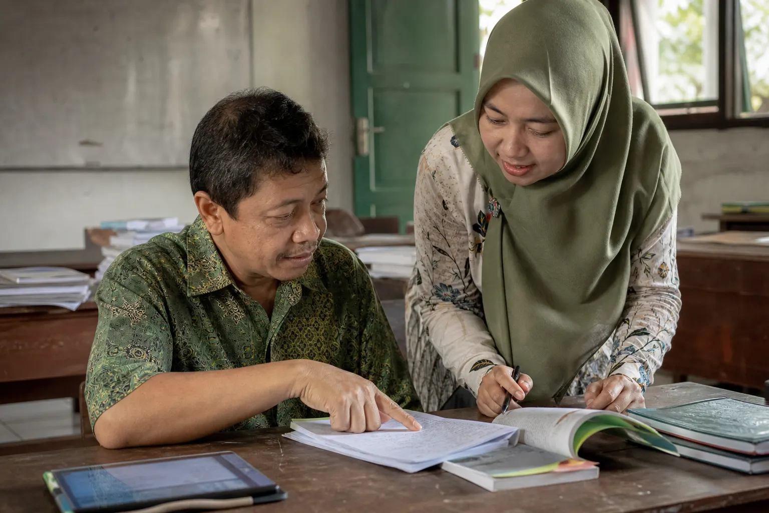 Dua guru meninjau catatan pembelajaran dan saling memberi umpan balik